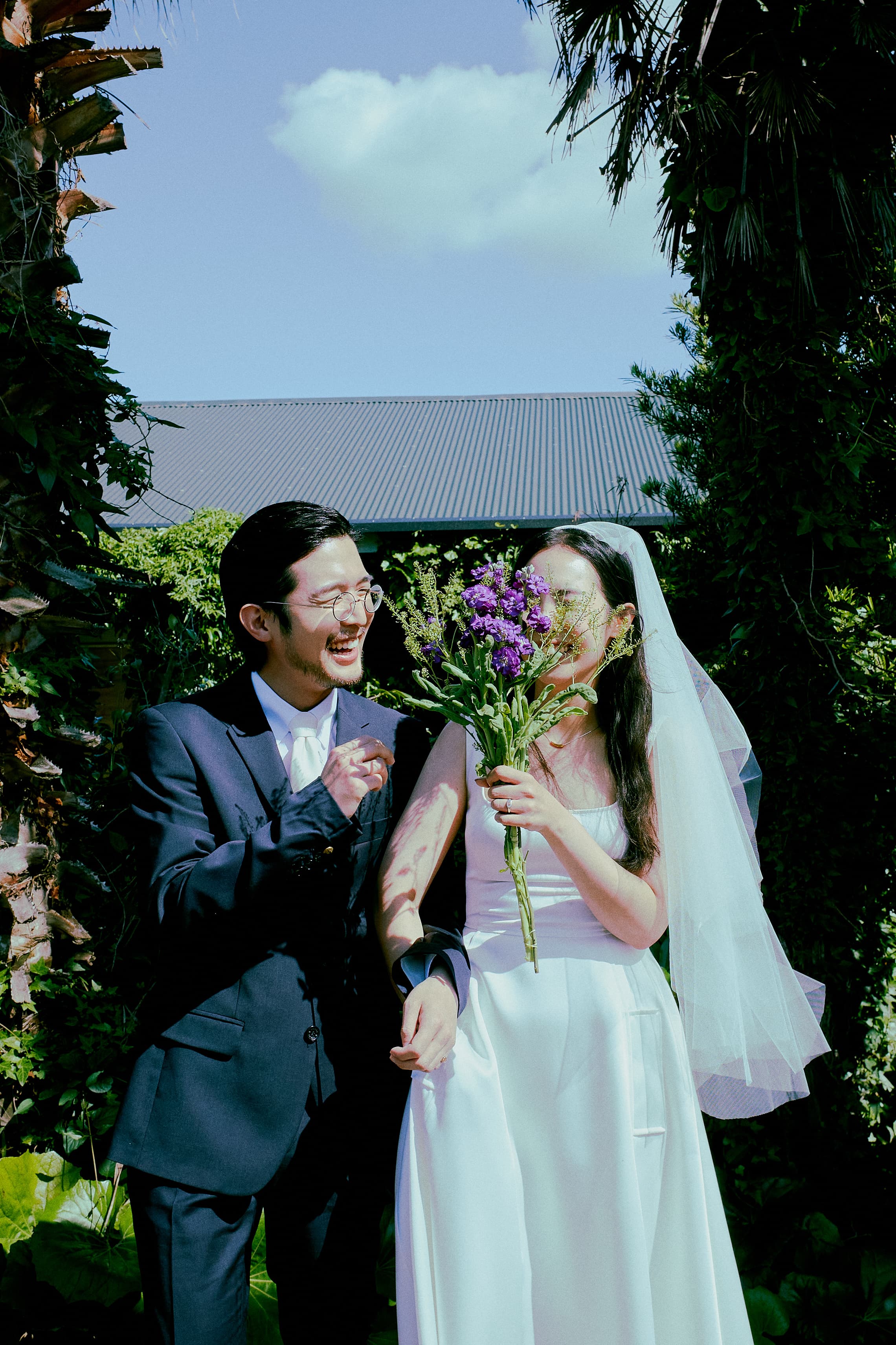 outro, 신부가 부케로 얼굴을 반쯤 가리고 웃고 있다.