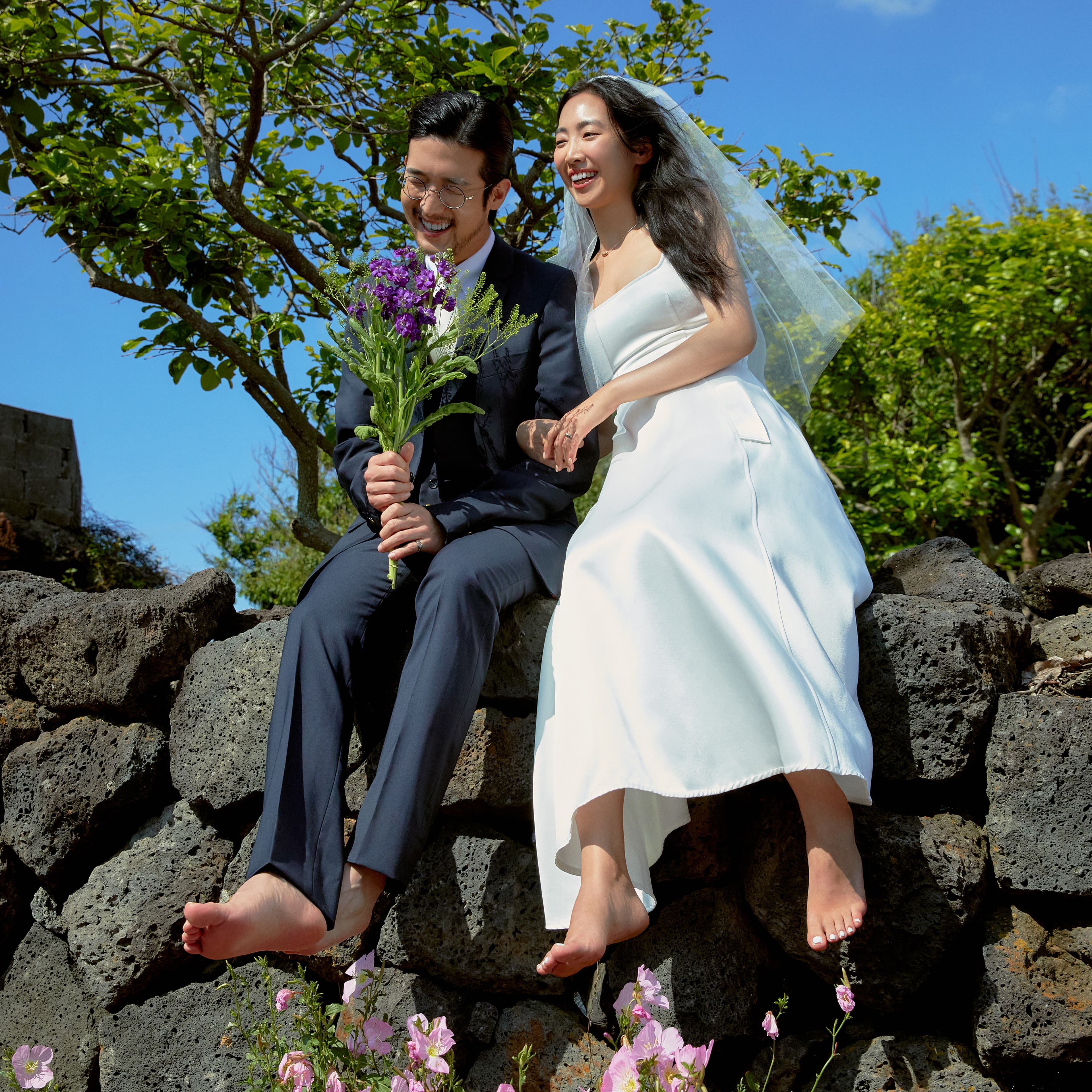 둘이 돌담에 앉아 환하게 웃고 있다.